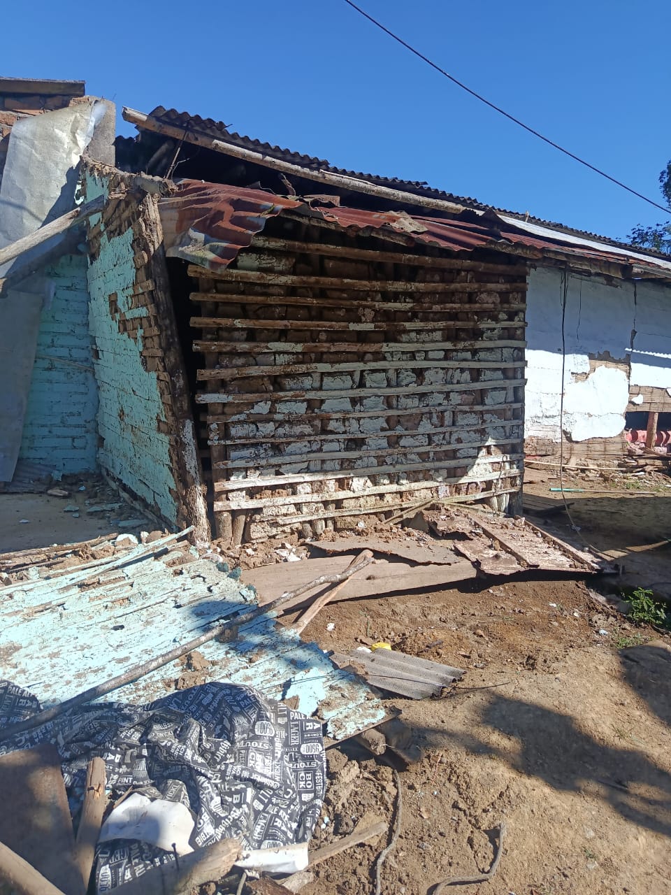 Muro de bahareque derrumbado que deja a la vista la estructura de guadua de la casa