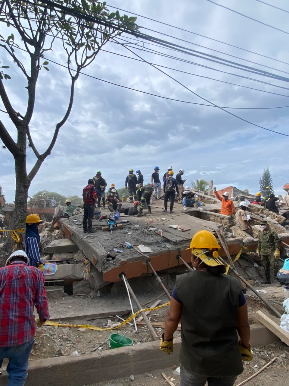 Decenas de personas y equipos de socorro trabajando entre los escombros durante el día