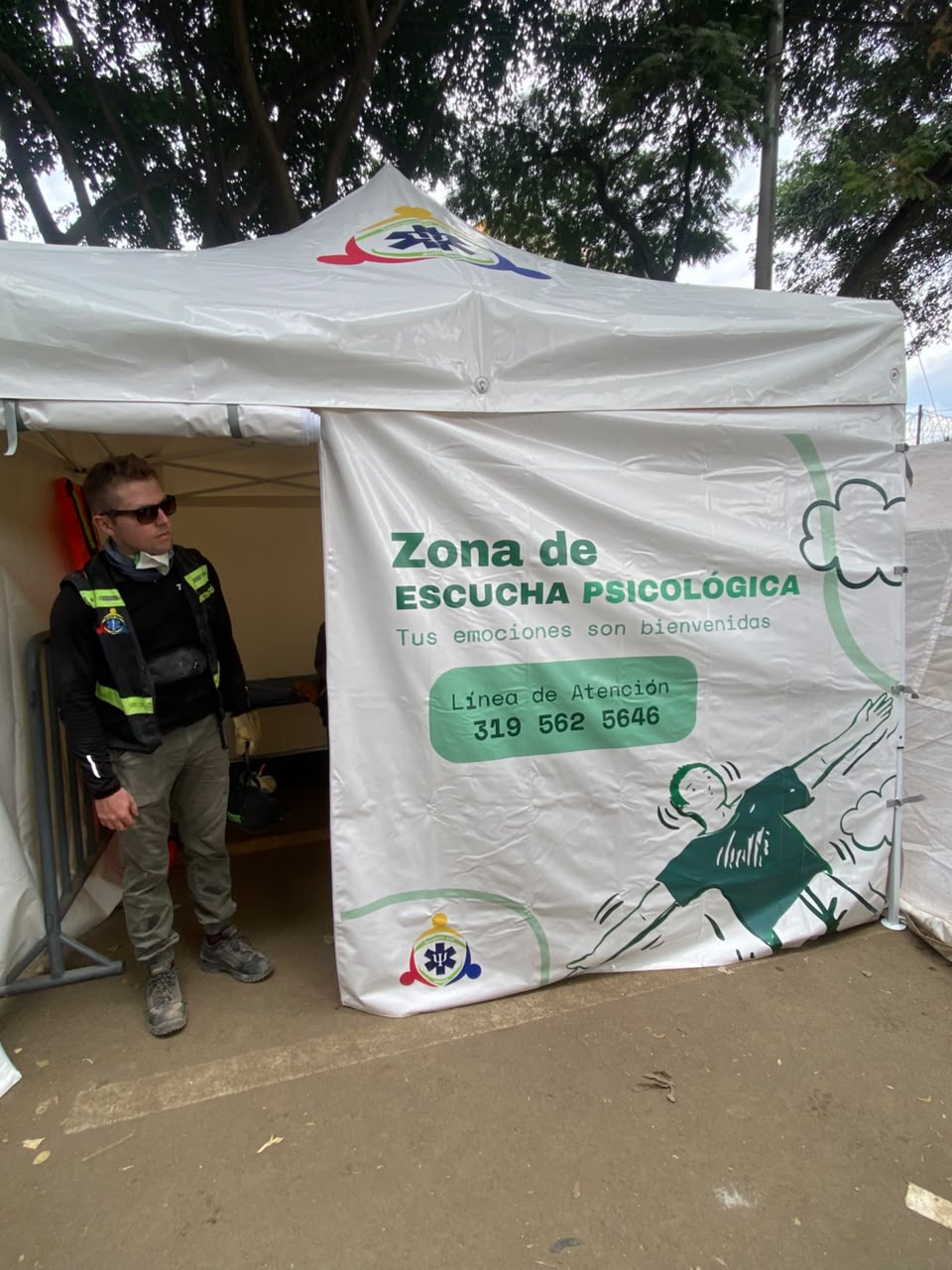 Carpa con el aviso “Zona de escucha psicológica: tus emociones son bienvenidas” y su línea de atención