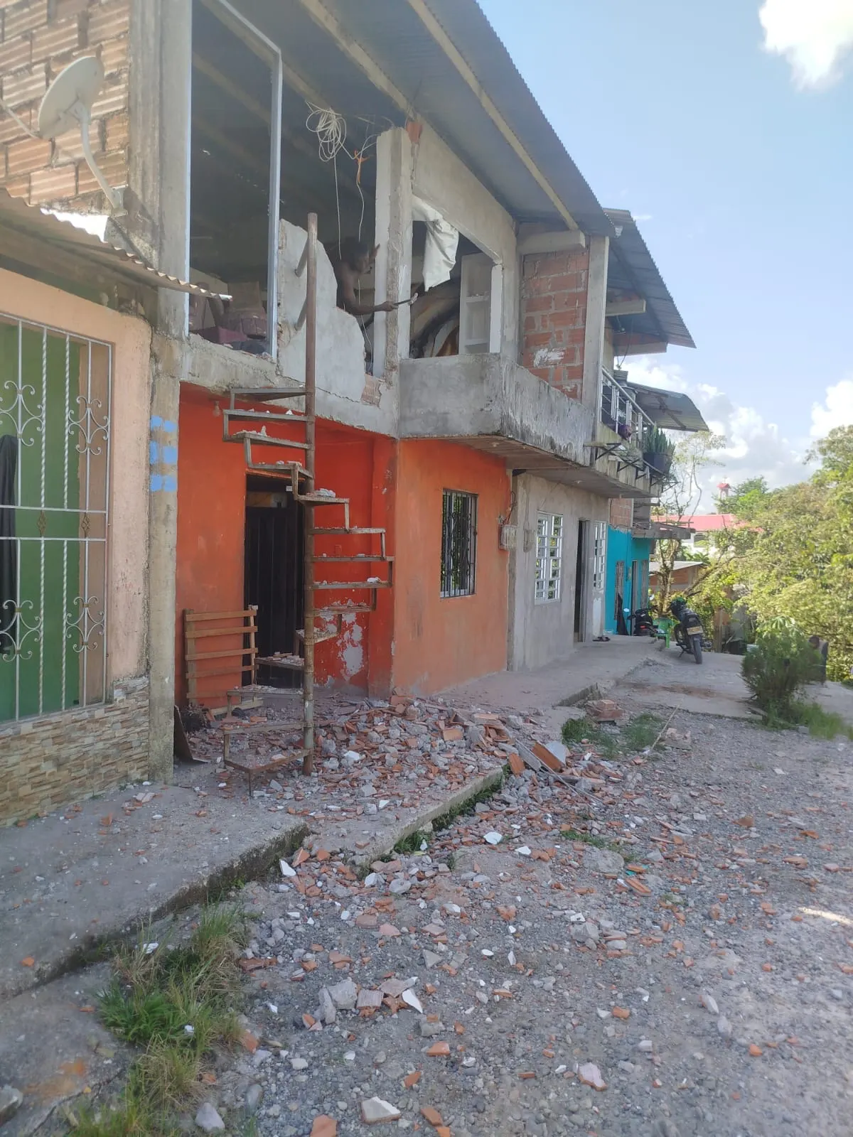 Calle de barrio cubierta de escombros de ladrillo frente a viviendas agrietadas